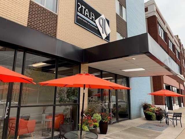Outdoor seating area with tables and red umbrellas at Flats on Jefferson apartments for rent