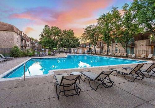 An outdoor pool with lounge chairs and umbrellas with a beautiful sunset at 450 Green apartments